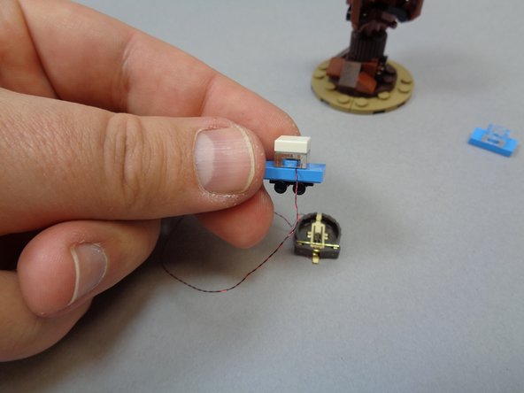 Take the pre-lit car and battery holder assembly out of its bag, and as shown in the second photo, remove the white top and black wheels from the car in your LEGO® set and transfer them to the pre-lit car as shown in the third photo.