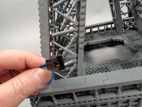 Take the male plug of the inter-level connecting board, and as shown by the purple arrows in the second photo for this step, pass it inside the pillar and out the bottom right.