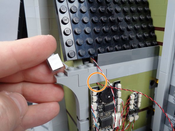 As shown by the orange circle in the third photo for this step, make sure the light bluish gray bricks are re-attached to the green wall bricks with the LED light wire running between the studs of the wall bricks.