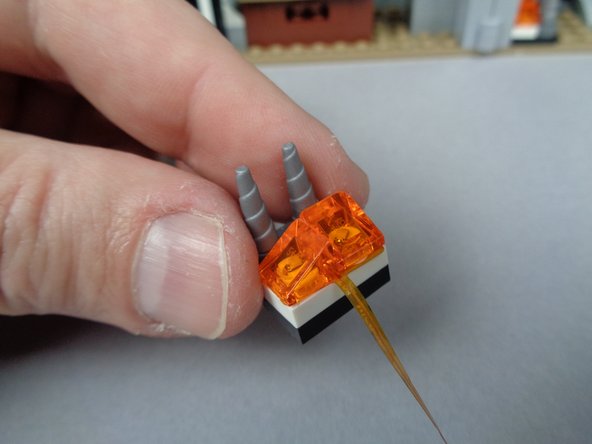 As shown in the first photo for this step, place the flame assembly on top of the two white LEGO studs in the fireplace.