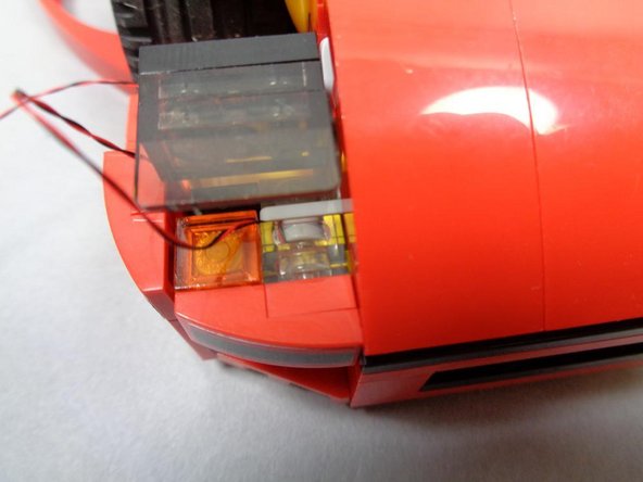 As with the main headlight assembly, make sure the LED is in the center of the LEGO® stud opening as shown by the blue arrow in the second photo, and prepare the LED by bending its wires over the edge of the stud opening with your fingernail.