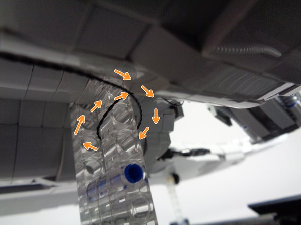 As shown by the orange arrows in the second photo, wrap the power wire several times around the clear base supports to provide tension relief.