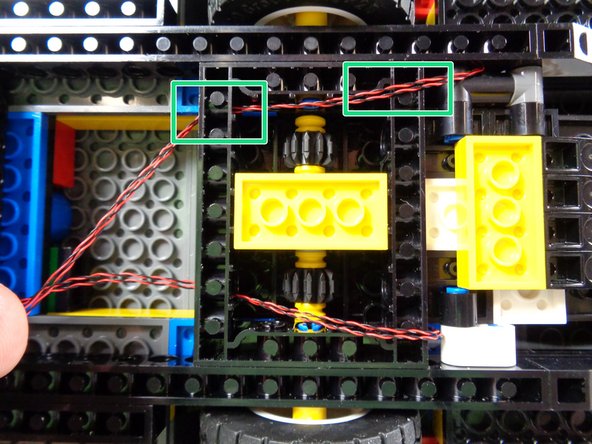 As shown by the two green rectangles in the first photo, route the two light wires over the first Techinc frame and through the hole in the second frame.