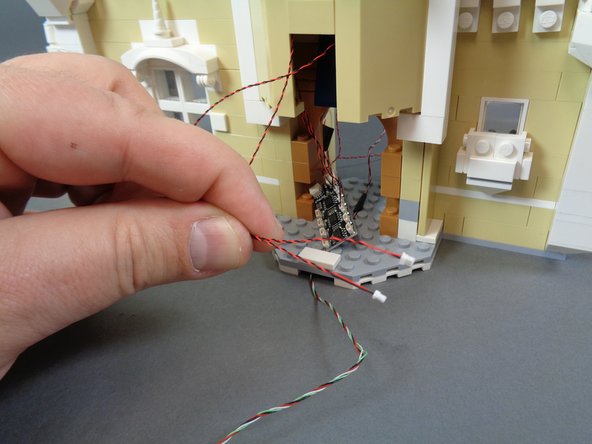 As shown in the first photo, pull the wires for the spinning room light and the kitchen ceiling light down and out the front of the castle.