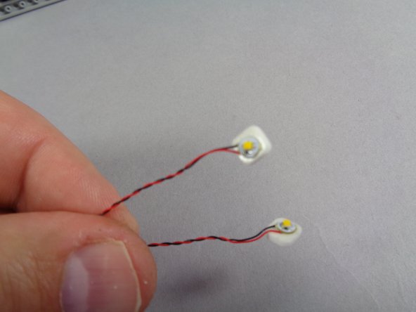 As shown in the second photo for this step, take two small sticky squares and stick them to the back sides of the two Pico LEDs.