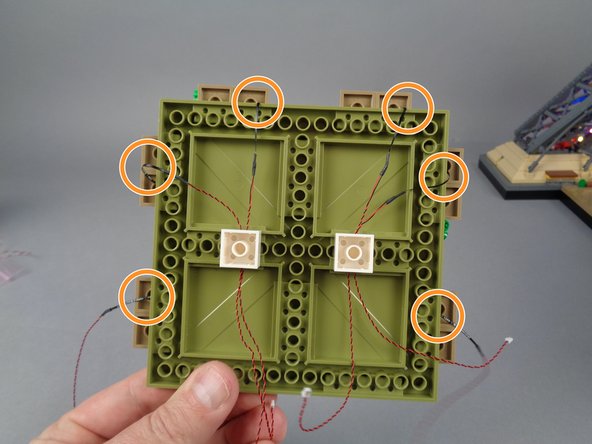 In order to prevent damage to the LED light wires when re-attaching the large plates, you can use the two white 2x2 bricks you removed in Step 83 to hold the wires, as shown in the photo for this step.