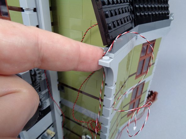 As shown in the photos for this step, run the 3-wire cable up to the roof of the mansion and use the 1x1 Technic brick to hold it in place.