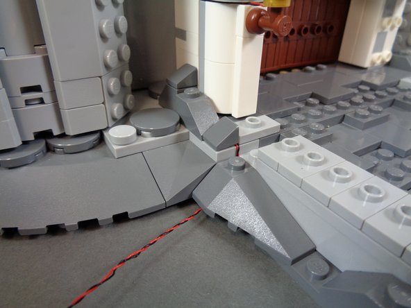 As shown in the photos for this step, continue re-attaching the parts you removed earlier to fully hide the light wires.