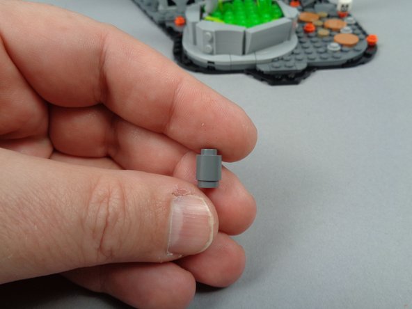 The third photo for this step shows the dark bluish gray round 1x1 brick that should be the last remaining part provided in your &quot;Brick Parts&quot; bag.  You'll need this part toward the end of the setup.