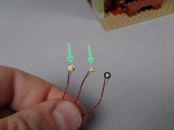 As shown by the green arrows in the first photo, you will have a bag with three Pico LED lights in  your BOX #3: two of these will have white bases and one will have a black base.  The green arrows point to the LED lights you want to use for these next steps: the two with the white bases.