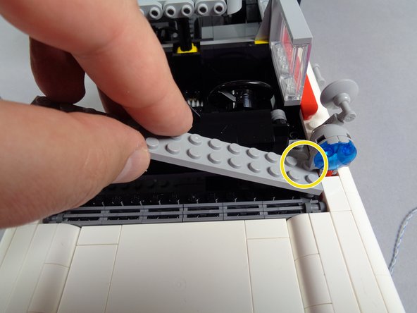 As shown in the second photo for this step, carefully re-attach the light bluish gray plate between the hood and dashboard.