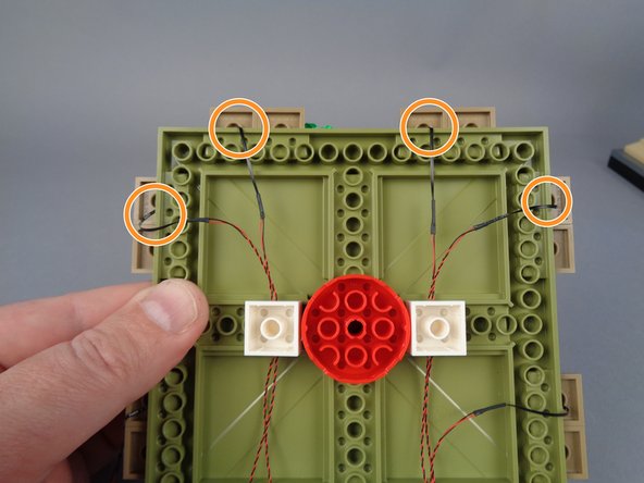 In order to prevent damage to the LED light wires when re-attaching the large plates, you can use the three bricks you removed in Step 12 to hold the wires, as shown in the photo for this step.