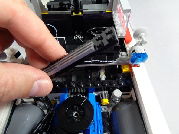 As shown in the first photo for this step, remove the long black plate with silver pieces on top.