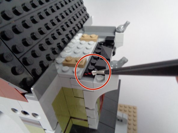 As shown by the red circle in the second photo, carefully pull the plug through the gap in the front mansion wall created earlier by the slope piece.