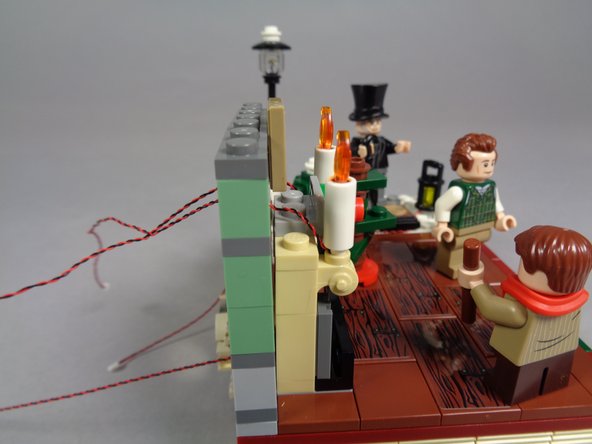 As shown in the first and second photos, the light wires for the two candles should now pass through the back of the chimney.