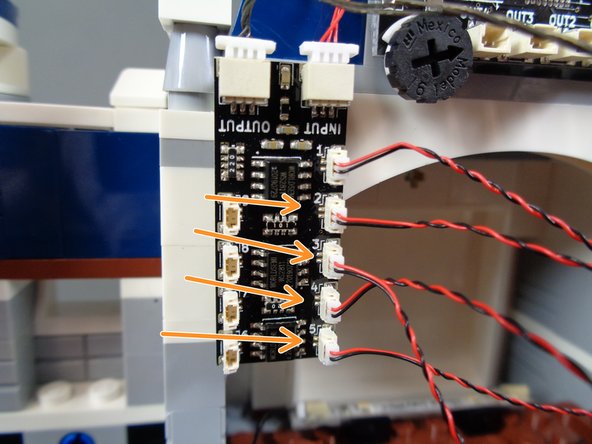 As shown by the orange arrows in the first photo, connect the four tower lights to plugs #2, #3, #4, and #5 on the BRANCH09X adapter board.