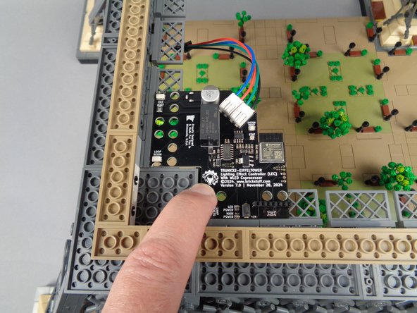 Position the main controller in the corner of the tower base as shown in the first photo for this step.