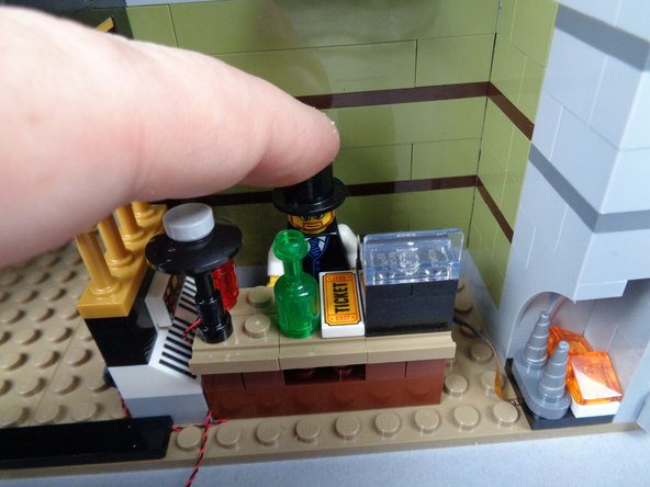 As shown in the photos for this step, re-attach the front desk and the minifigure.