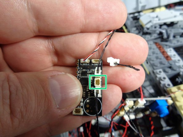 As shown by the green rectangle in the first photo for this step, carefully disconnect the black wire from the middle side connector on the old TRUNK05 controller.