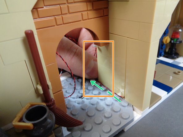 As shown by the orange rectangle in the first photo, remove the light brown stove frame along the wall, and route the candelabra light wire toward the front of the castle (see the green dotted line).