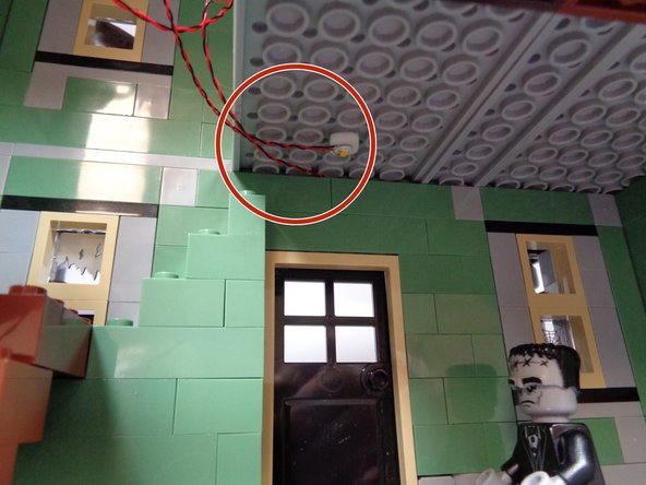 Re-position the second floor center section you removed earlier.  As shown in the first photo, make sure the front porch light and the first floor warm white Pico LED light wires  pass toward the left and to the side of the floor section as shown by the red circle.