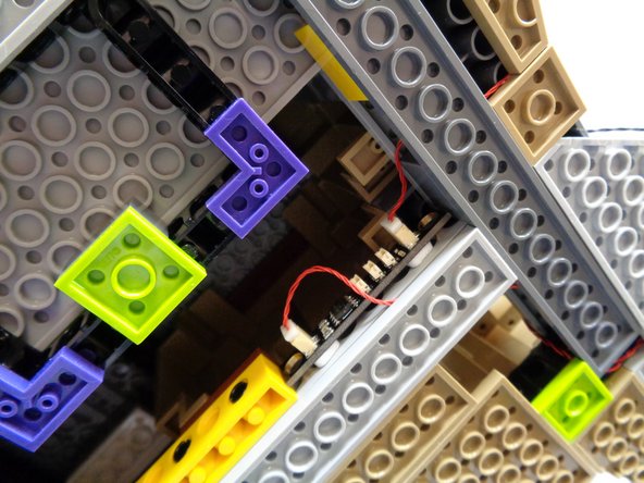 As shown in the second and third photos, use two small sticky squares to mount the BRANCH09 adapter board on the side of the Technic brick in the castle base.