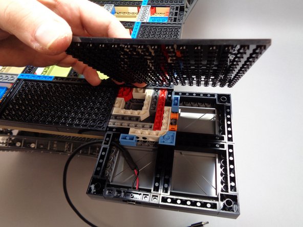 As shown in the second and third photos for this step, carefully re-attach the large black base plate to the tower.