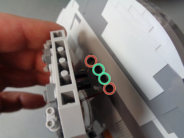 As shown in the first photo, re-attach the laser cannon to the main mount, being careful to pull the laser light wires (red circles) through the holes so there is no extra slack sticking out.