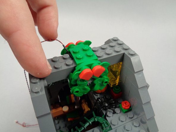 As shown in the first photo for this step, replace the second roof cross-beam, making sure the LED light wire passes up and between the beams as shown by the red circle in the second photo.