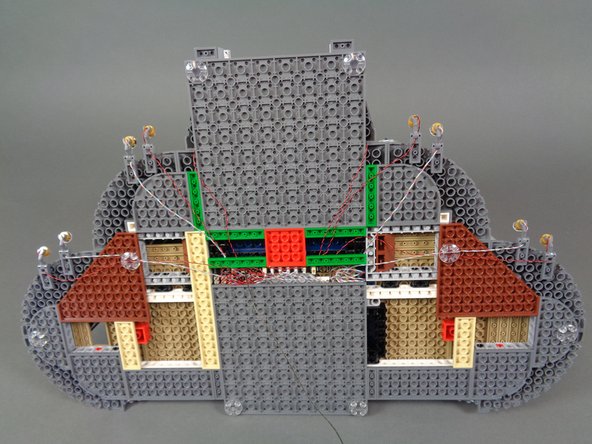 As shown by the blue arrows in the second photo, you can further secure spotlight wires by removing plates from the base of the castle, carefully passing wires between (not on top of) studs, an replacing the plates.