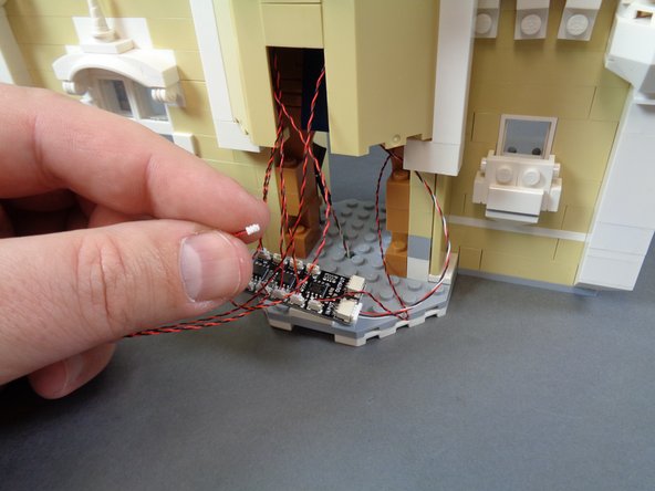 As shown in the first photo for this step, pull the magic room light wire out through the front of the castle.