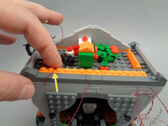 As shown by the yellow arrow in the second photo, route the wire for the left torch between the studs of the long orange plate.