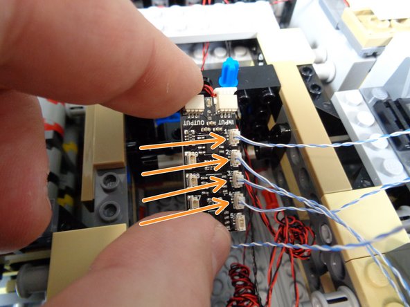 As shown by the four orange arrows in the photo for this step, connect the four docking bay lights to plugs #1, #2, #3, and #4 on the third BRANCH09X adapter board.