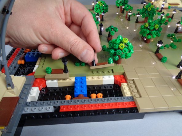 If the two lamp posts shown by the orange boxes in the first photo for this step separated along with Panel 4L, you will need to re-position them onto the large center Panel 4 as shown in the second and third photos.