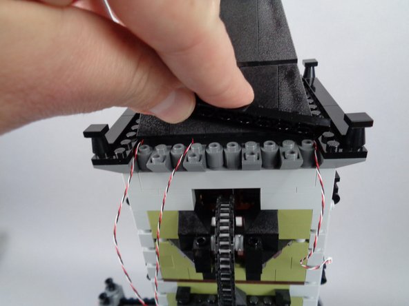 As shown in the photos for this step, replace the large black plate and large black tile you removed earlier onto the top of the roof.