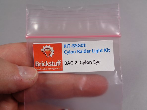 Remove the pre-lit eye assembly from Bag 2 as shown in the first photo for this step.