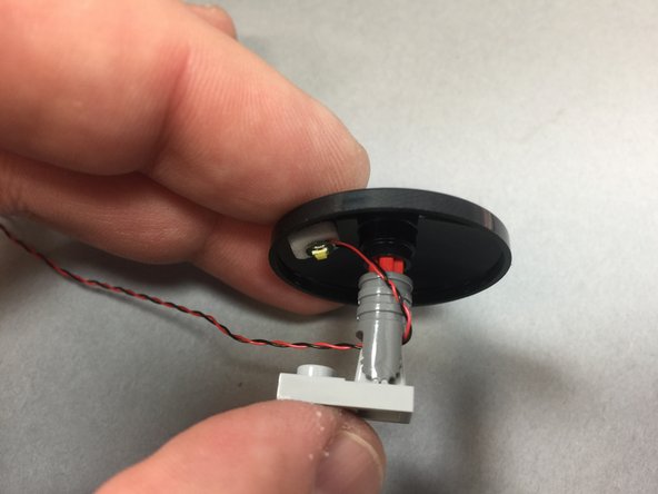 As shown in the photos for this step, remove the Dejarik holochess table from the front interior room, attach a Pico LED light to the underside using a small sticky square, and thread the LED light wire under the table and secure with the light bluish gray foot plate part.