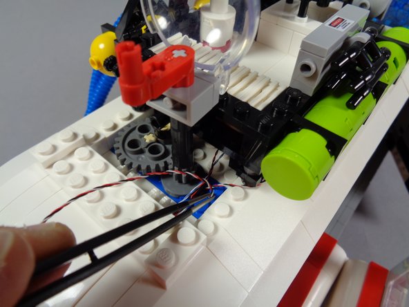 This hole will now be getting crowded with wires, so you will likely need to use tweezers or your toothpick again (as in the third photo) to gently push the wire down through the roof.  It can help to try passing the plug sideways, or at a different angle, to find a passage through the hole.