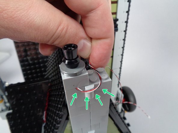 As shown in the first photo for this step, close the two halves of the mansion and bend the wire back toward the second half.