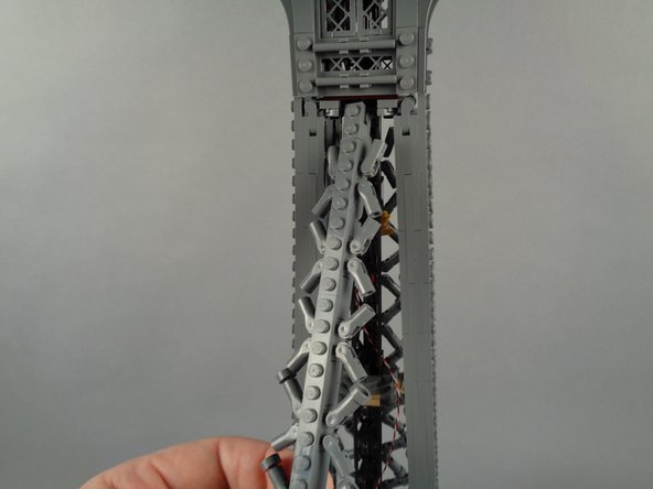 As shown in the photos for this step, re-attach the top rear tower frame section.