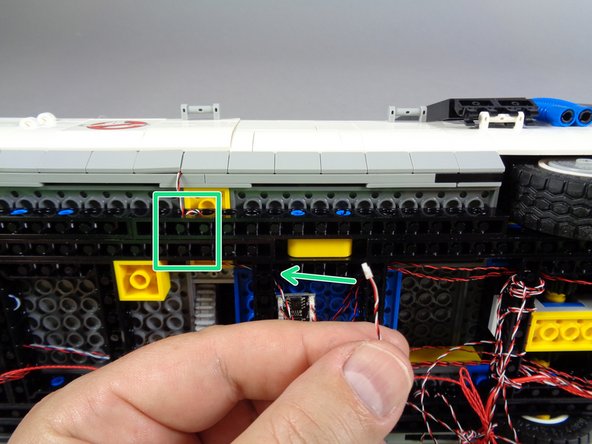 As shown by the green rectangle in the first photo, pass the switch wire through the holes in the Technic frame near the door, and loop several times to provide strain relief.  Then, route the wire through the hole in the frame behind the door, as shown by the green arrow.