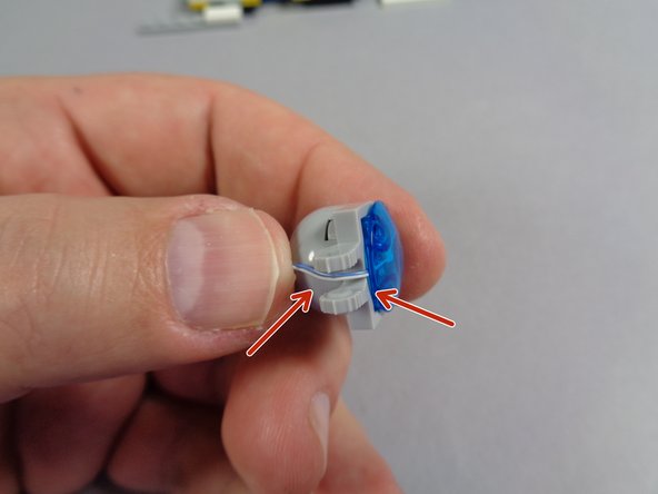 As shown  by the red arrows in the second photo, pass the LED light wire through the center of the clip below the light.