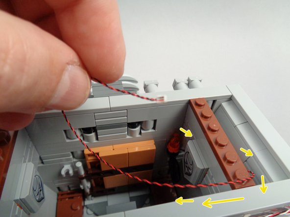 As shown in the first photo for this step, re-attach the first torch to the inner wall, then pass the light wire behind the inner side wall and up out the top of the town hall.