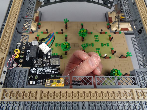 As shown in the first photo for this step, carefully reach under the center of your tower to find the loose control cable coming from the first adapter board and first set of light strips.
