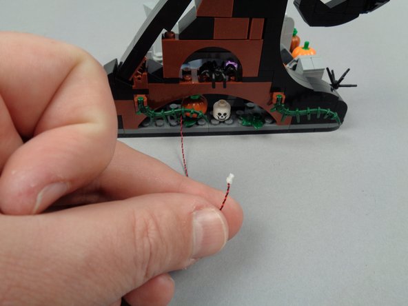 As shown by the orange arrows in the first photo for this step, pass the LED light wire under the wave assembly.