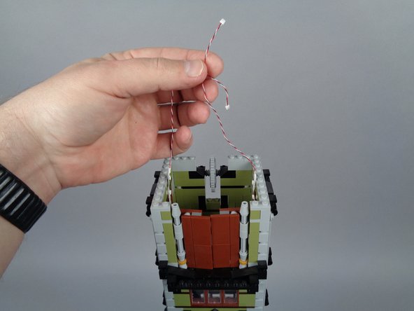 As shown in the third photo for this step, you should have both light strip wires extending out the top opening.