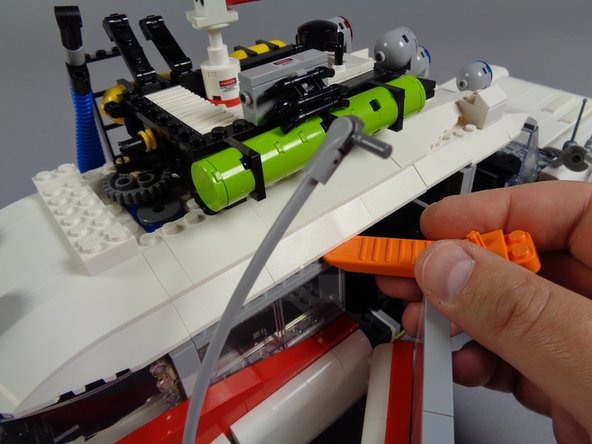 As shown in the second photo, you can use the brick separator that came with your LEGO set to loosen the sides of the rear roof section.