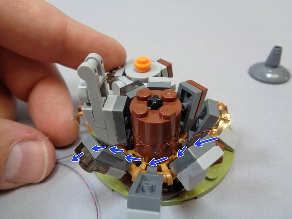 Re-attach the large front window piece and run the light wires around the center core as shown by the blue arrows in the second photo.