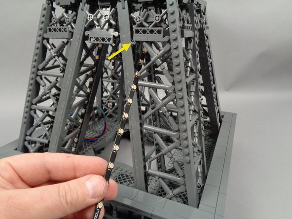 As shown in the first photo for this step, take the light strip connected to output #1 on the adapter board, and pass it through and into the center of the third pillar.