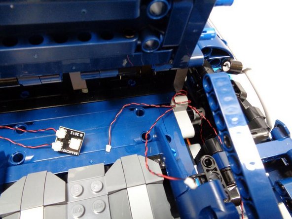 As shown in the second photo, route the wires from the front and rear turn signals through the gray Technic bracket.  If you have extra cable, wrap both wires around the bracket to take up the slack.